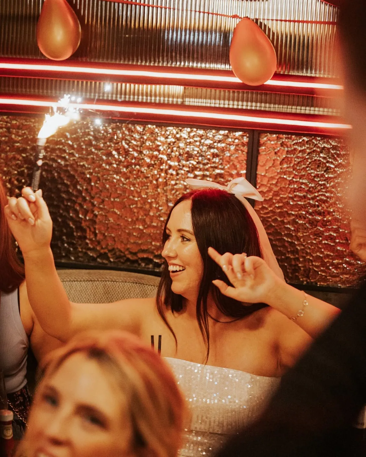 A celebration at Jack's with sparklers and balloons under red neon