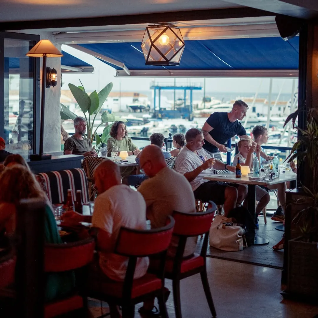 Diners at Jack's in the evening with the marina and boats visible behind