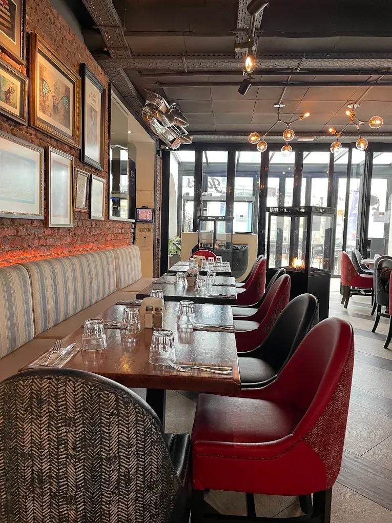 The dining room at Jack's Benalmádena with red leather chairs, brick walls and framed pictures