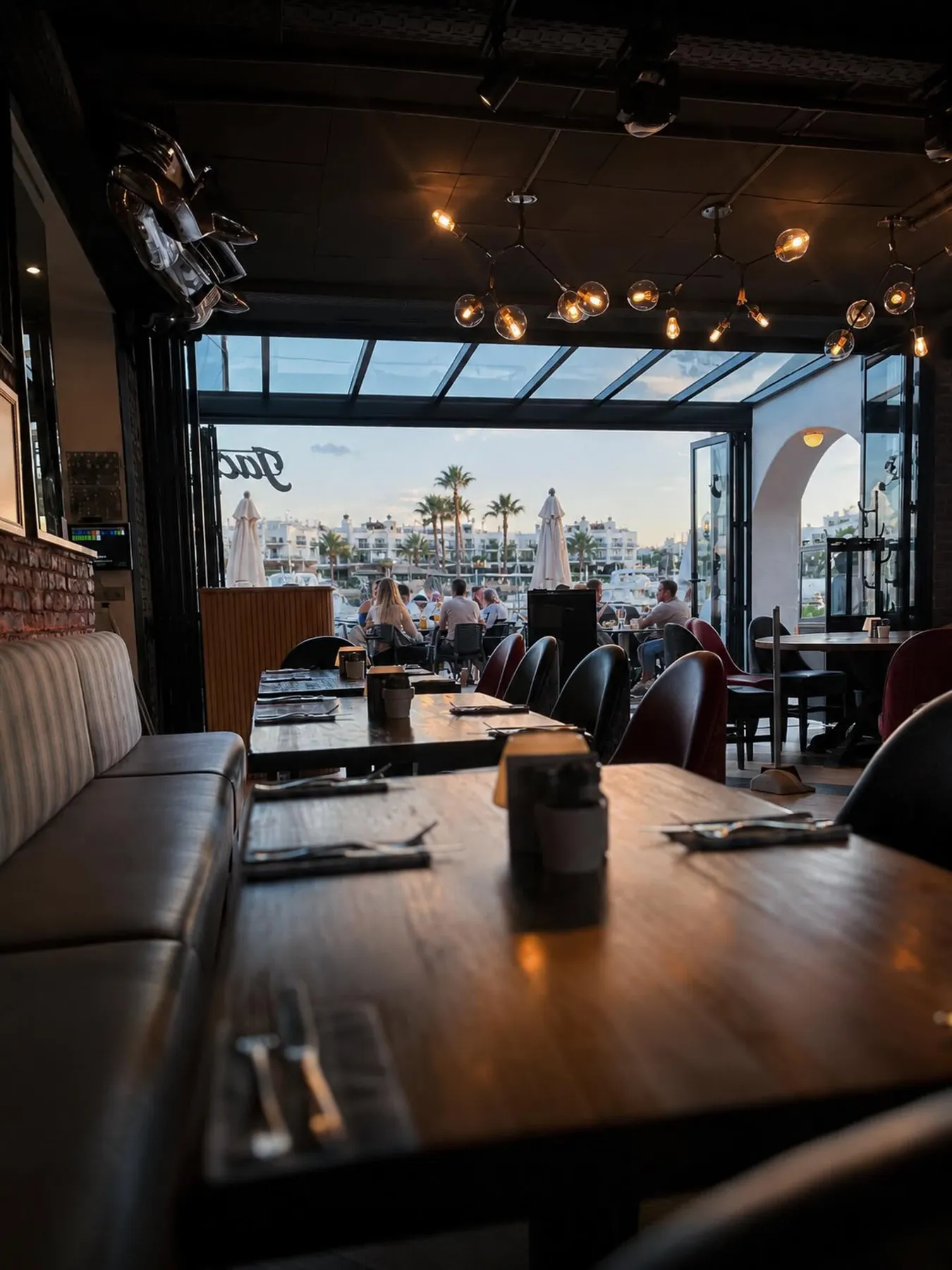 Inside Jack's Benalmádena at golden hour, looking out through open doors to Puerto Marina