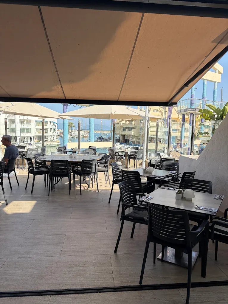 The Jack's terrace in Benalmádena during the day, with black furniture and Puerto Marina beyond