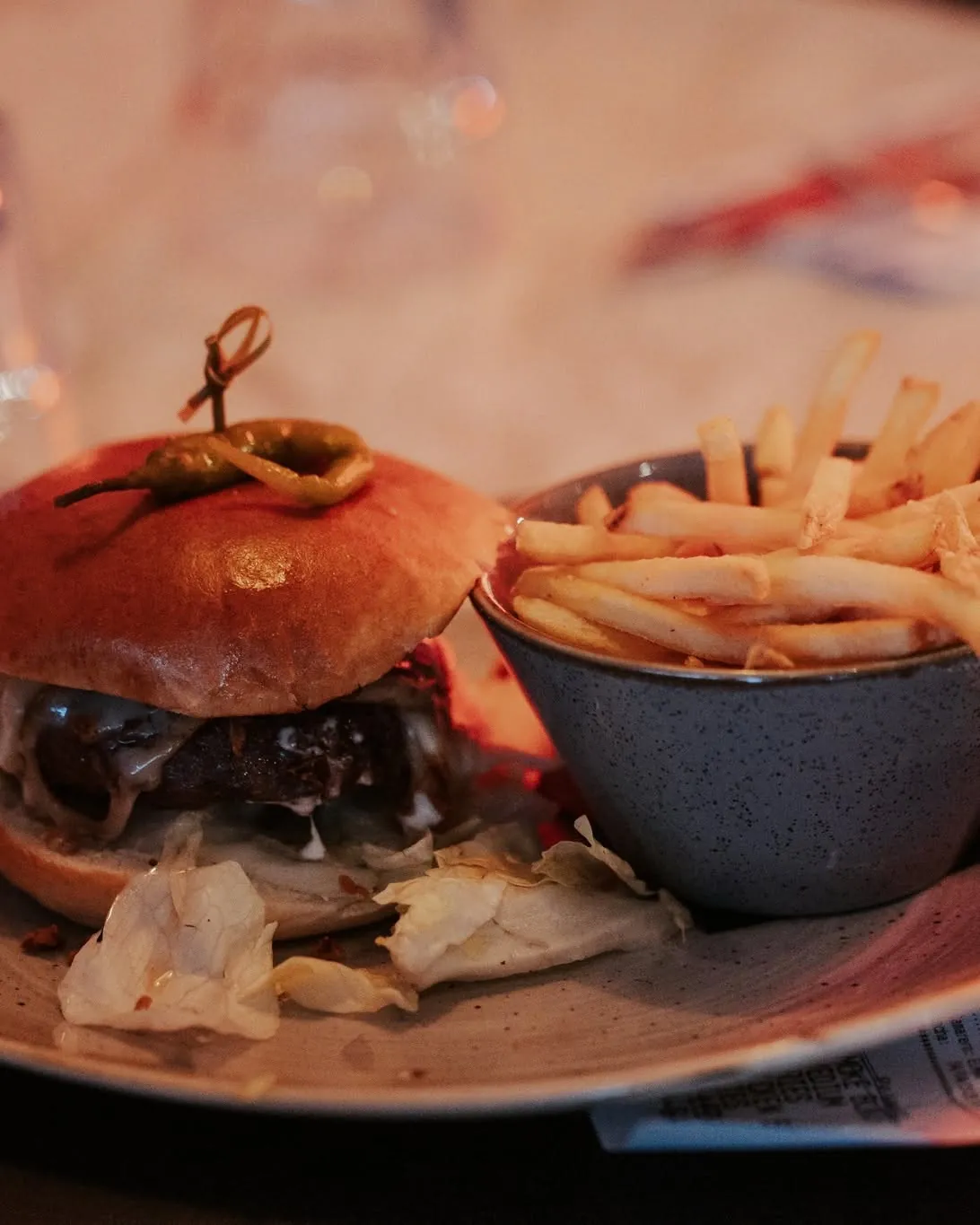 A cheeseburger and fries under warm red light at Jack's Benalmádena