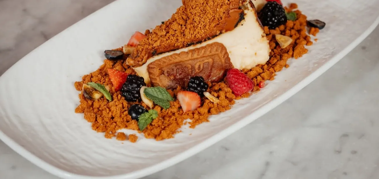 A slice of Lotus Biscoff Basque cheesecake with berries and crumb