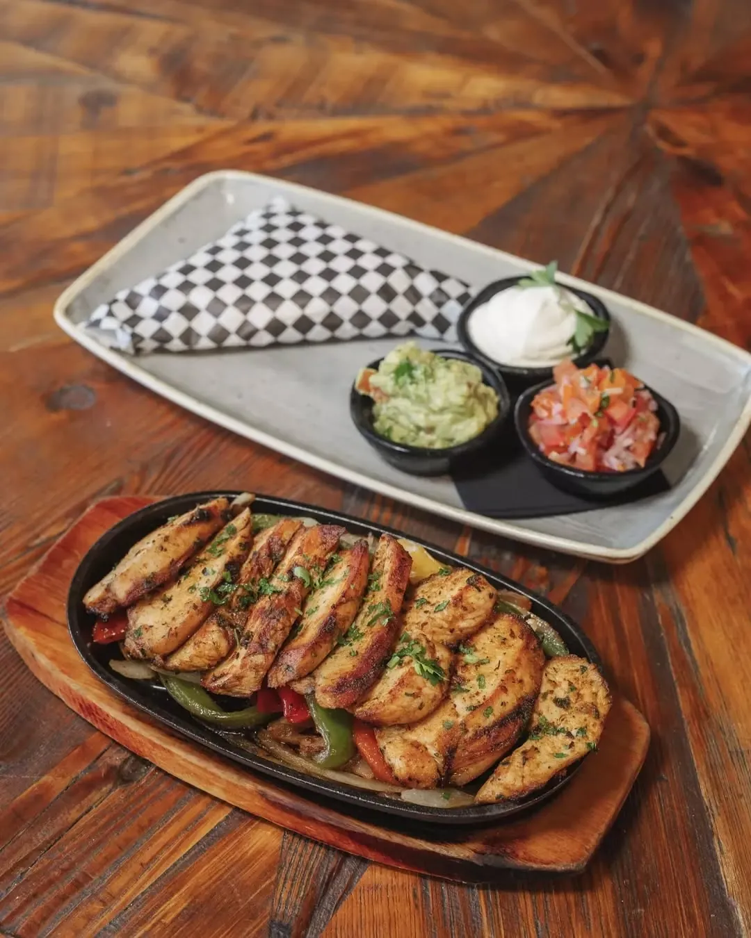 A sizzling skillet of chicken fajitas with guacamole, salsa and sour cream