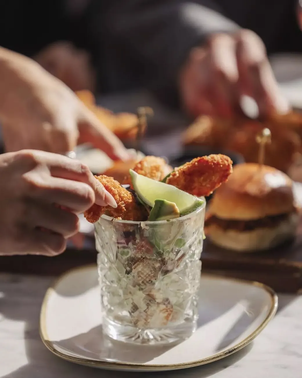 Crispy cajun prawns served in a cut-crystal glass with avocado and lime