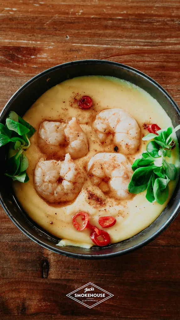Grilled pil pil prawns on buttery corn porridge with lamb's lettuce and chilli