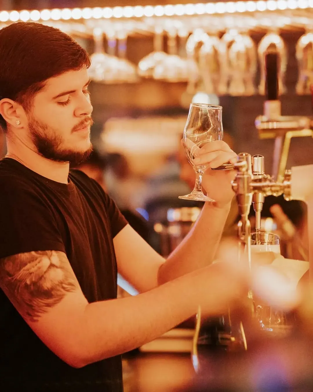 A bartender pouring a beer under the warm lights of the Jack's bar