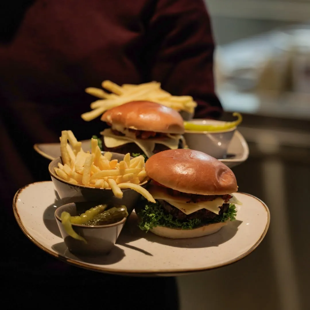 A member of the Jack's team carrying two plates of burgers and fries